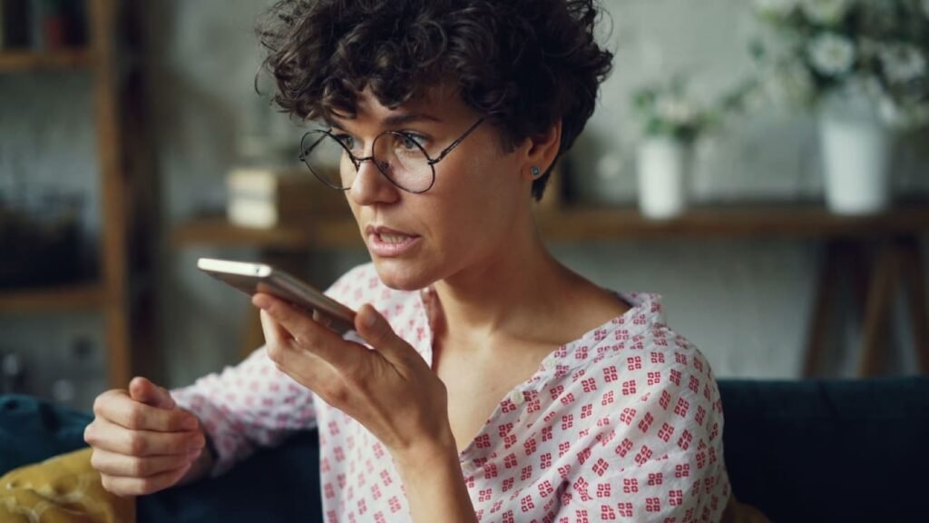 A woman at home speaking into her phone's voice assistant